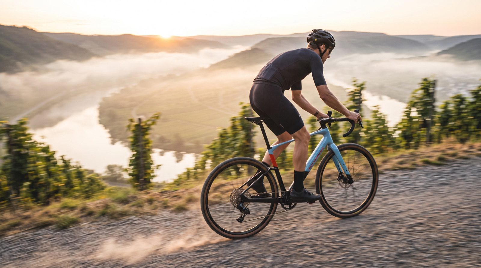 E-Gravelbike-Fahrer auf Schotterweg über der Mosel bei Sonnenaufgang