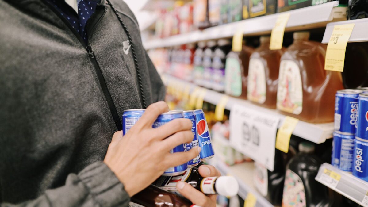 Person vergleicht im Laden die Angaben auf zwei Produktverpackungen