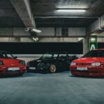 sh tuning - A group of three stylish sports cars parked under ambient lighting in an urban garage se