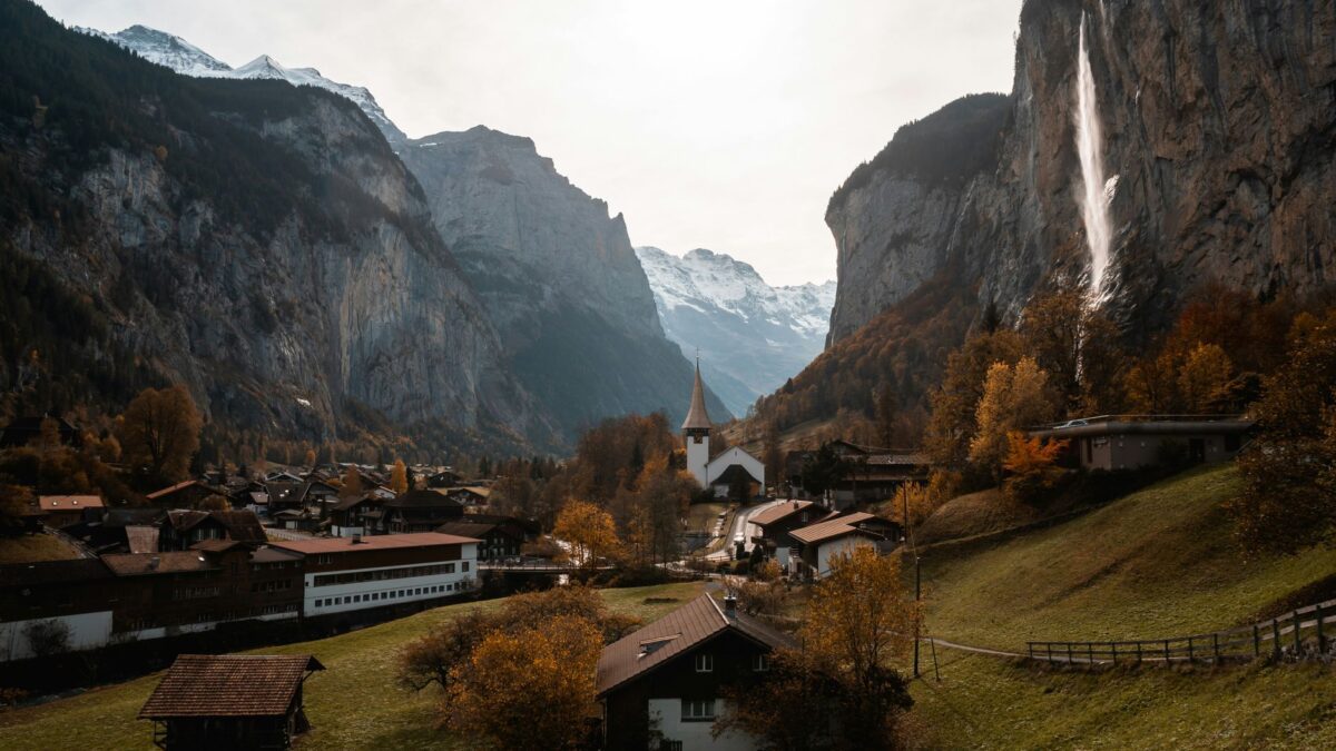 Wohnhäuser in einem Schweizer Dorf vor Bergkulisse im Herbstlicht