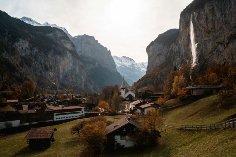 Wohnhäuser in einem Schweizer Dorf vor Bergkulisse im Herbstlicht