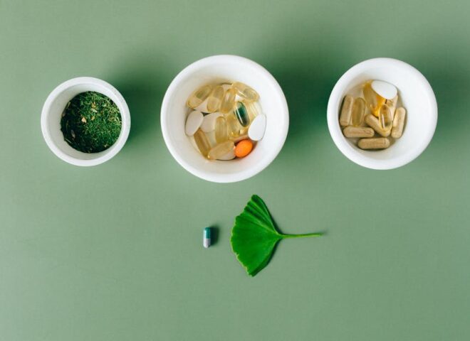 tisso - Flatlay of capsules and herbs in ceramic bowls on green surface.