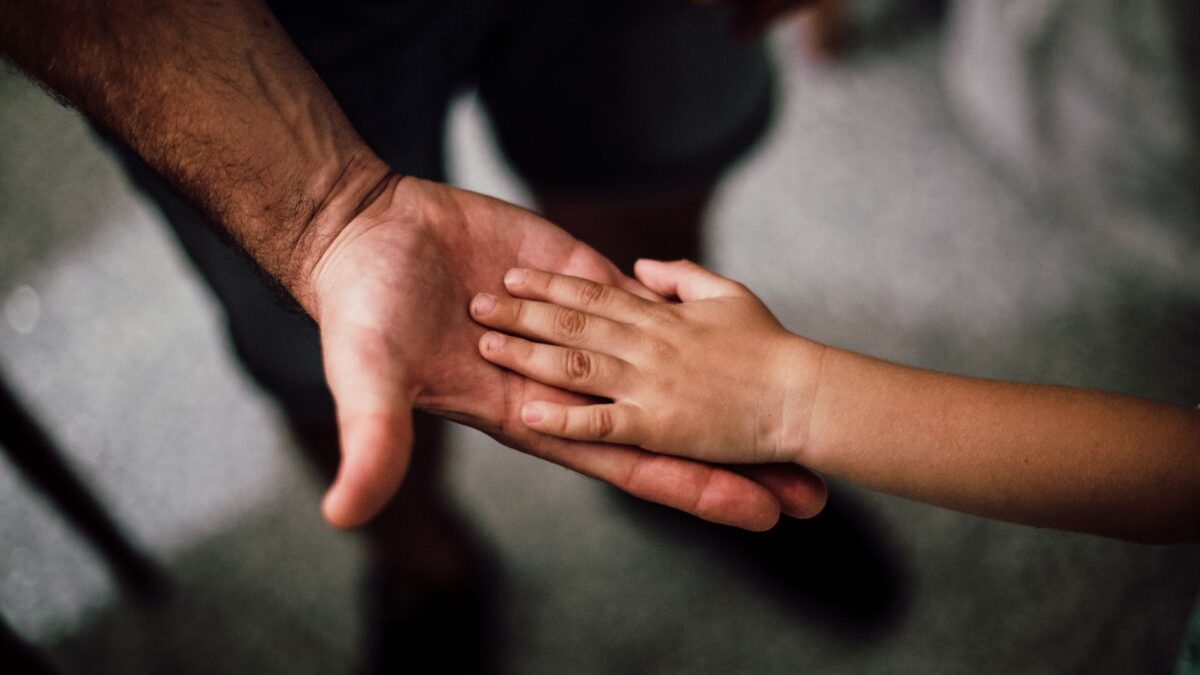 Hände von Vater und Kind als Symbol für Vaterschaft